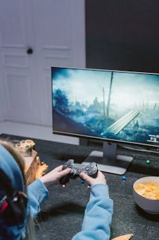 Focused teen playing a video game with controller at home, wearing headphones.